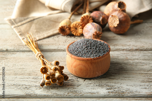 Poppy seeds and dried pods on wooden background