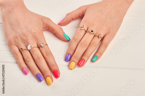 Manicured hands of young woman. Summer manicure and many rings with precious stones on female hands. Fashion manicure and luxury jewelry.