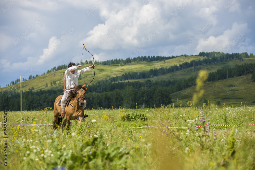 Obraz premium jockey, a rider on horseback jumps, dressed in an old folk costume of a nomad. archery on horseback