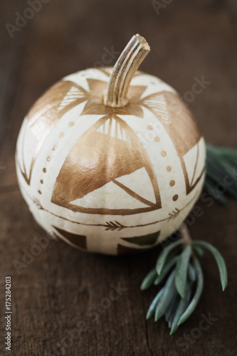 White pumpkin painted with gold geometric shapes photo