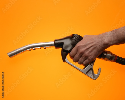 Obraz na płótnie Hand holding petrol pump on yellow background