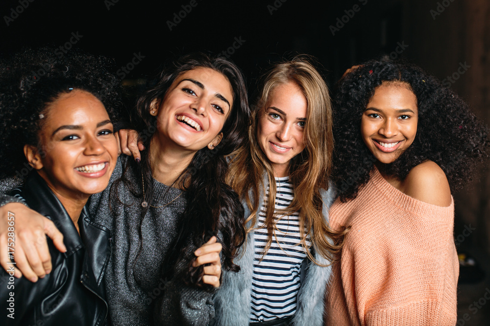 Obraz premium Four beautiful women looking at camera, standing outdoors at night