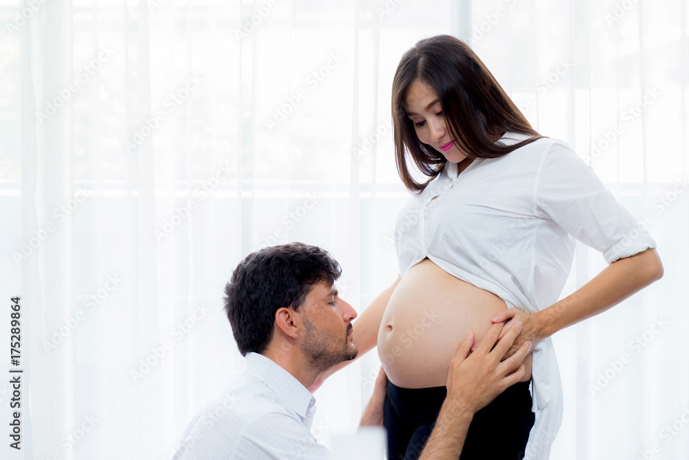 close up husband kiss pregnant woman belly - love of father to the unborn child.
