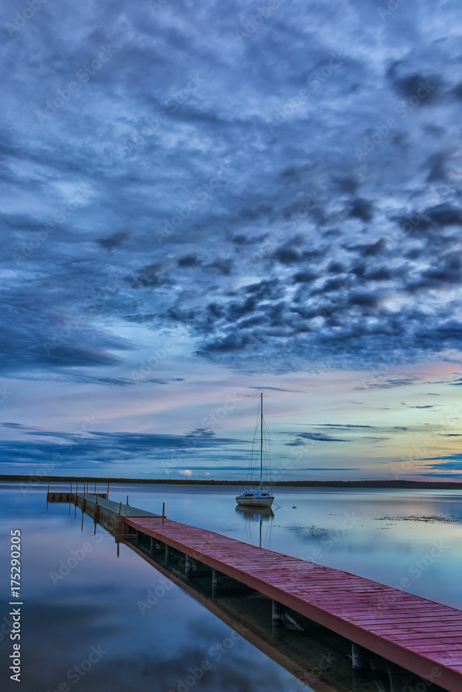 Travel Concepts. Amazing Picturesque Braslav Lakes in Belarus. With Small Sailing Boat on The Background. Taken During Blue Hour. Travel Concepts. Amazing Picturesque Braslav Lakes in Belarus. With Small Sailing Boat on The Background. Taken During Blue Hour.