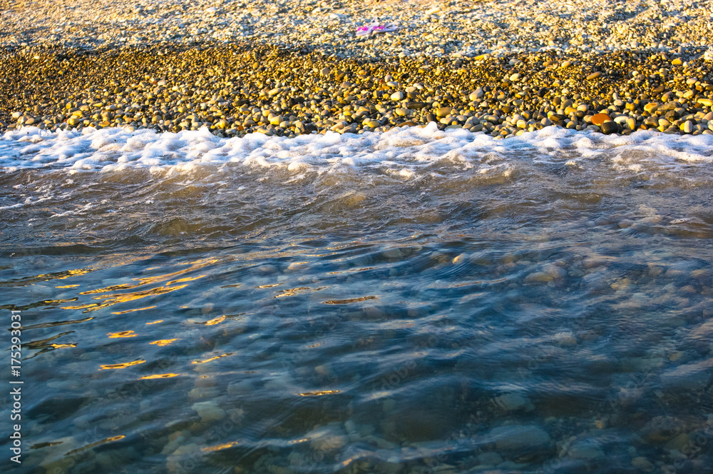 sea pebble beach with multicoloured stones, waves with foam sea pebble beach with multicoloured stones, waves with foam