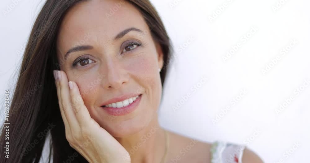 Portrait of young delightful model holding hand on face and looking gently at camera smiling slightly on white background. Portrait of young delightful model holding hand on face and looking gently at camera smiling slightly on white background.