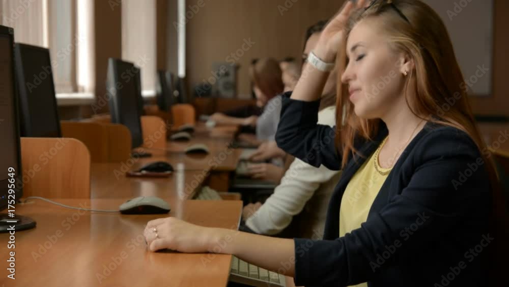 Young business woman with glasses working at computer. A group of young people in a computer room. Slow motion Young business woman with glasses working at computer. A group of young people in a computer room. Slow motion