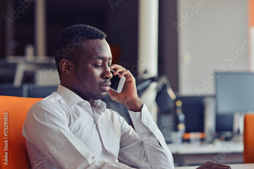 African American businessman on the phone sitting at the computer in his office