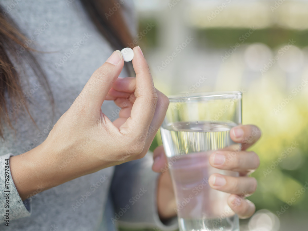 Close up of woman taking in pill with bokeh background. Health care and medical concept. Close up of woman taking in pill with bokeh background. Health care and medical concept.