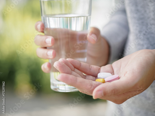 Close up of woman taking in pill with bokeh background. Health care and medical concept.