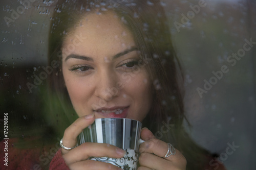 Beautiful woman is looking through the window on a rainy day.