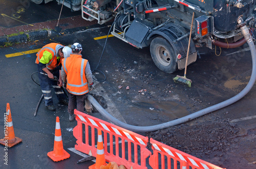 Road workers cleaning sewage in city street photo