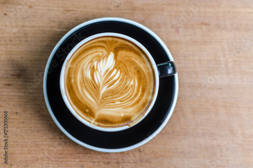 coffee latte art on wood table in cafe, selective focus top view