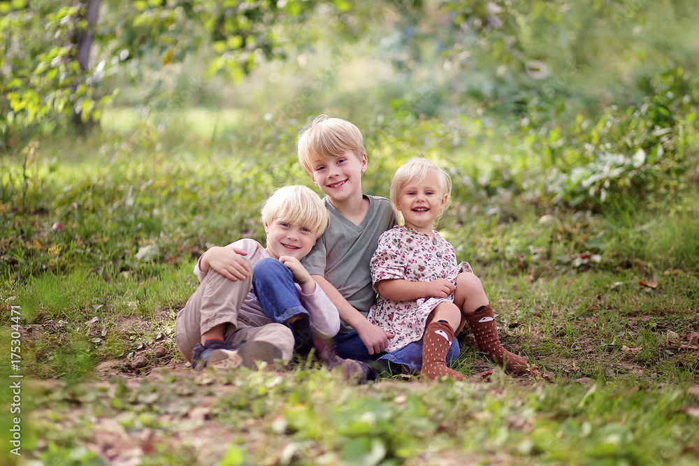 Family of Three Happy Young Children Posing Outside in Forest