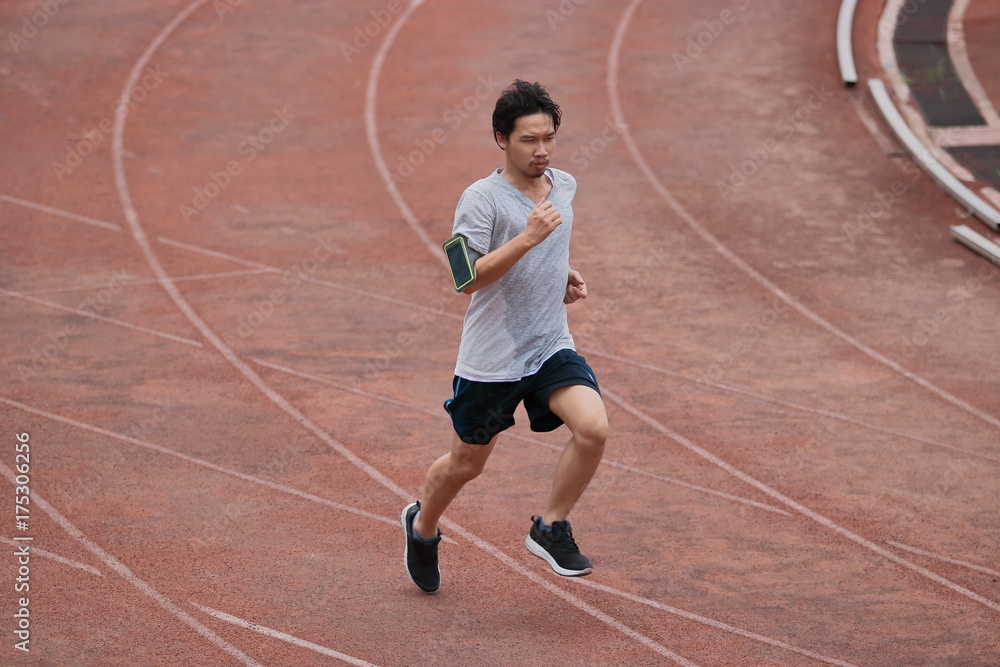 Athlete Asian man running on racetrack in stadium . Healthy active lifestyle concept.