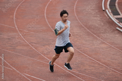Athlete Asian man running on racetrack in stadium . Healthy active lifestyle concept. © tuaindeed
