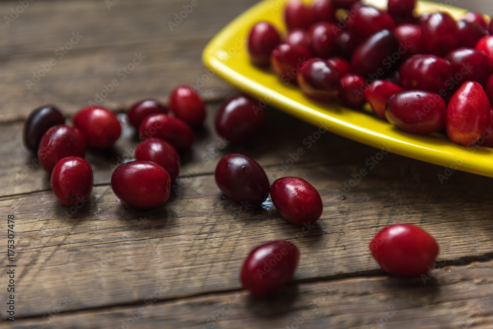  Cornelian cherry dogwood edible fruit in bowl on wooden surface