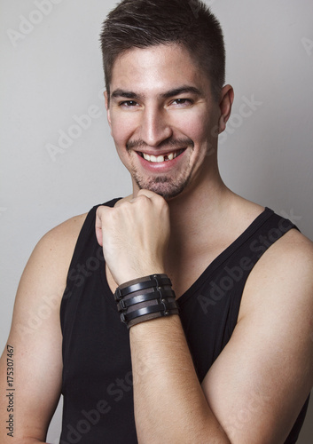 Portrait of young handsome man posing in front of camera with amazing big smile but with missing one tooth.