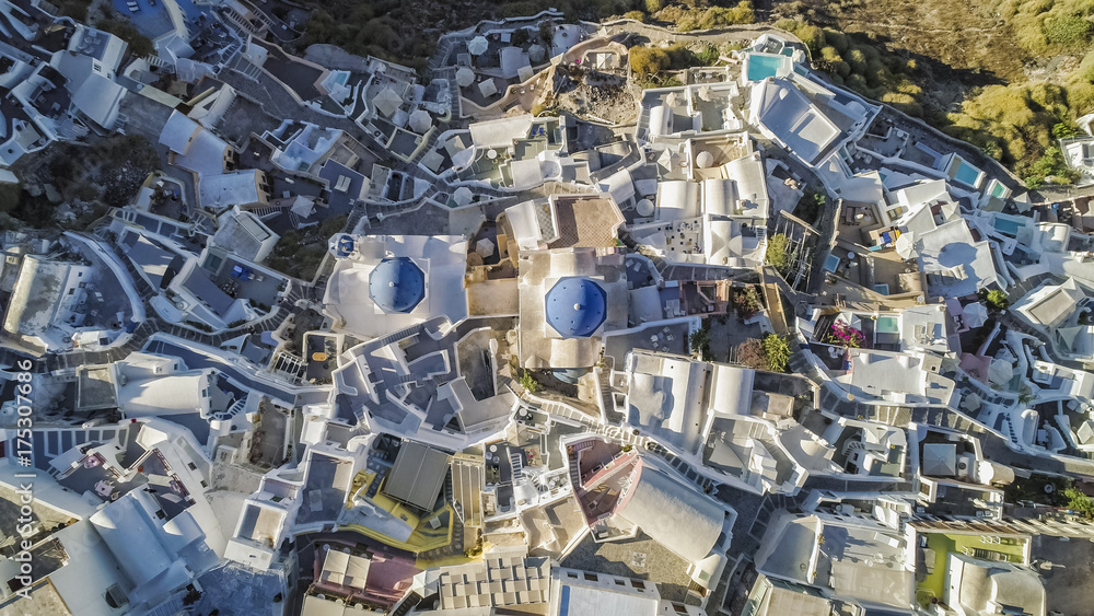 Aerial top view of white houses and blue dome church in Oia village, Santorini Island, Greece