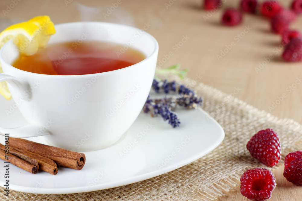 Mug of fruit tea and raspberries on cloth on the table Mug of fruit tea and raspberries on cloth on the table