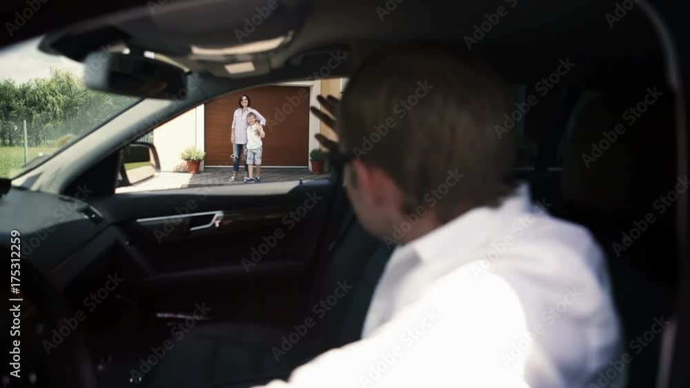 Father waves good-bye to his wife and son sitting behind the wheel of a car Father waves good-bye to his wife and son sitting behind the wheel of a car