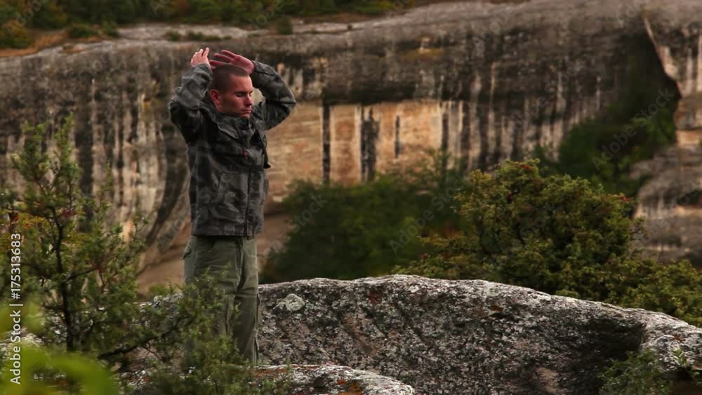 Man in military uniform performs breathing exercises in the mountains Man in military uniform performs breathing exercises in the mountains