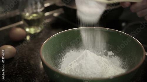 A cook sieves flour to make it airier before making dough photo