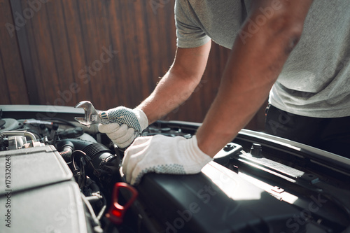 Close-up. A man is fixing a car with a wrench. White car © Bogdan