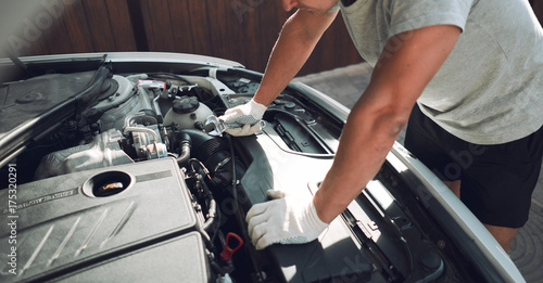 Close-up. A man is fixing a car with a wrench. White car