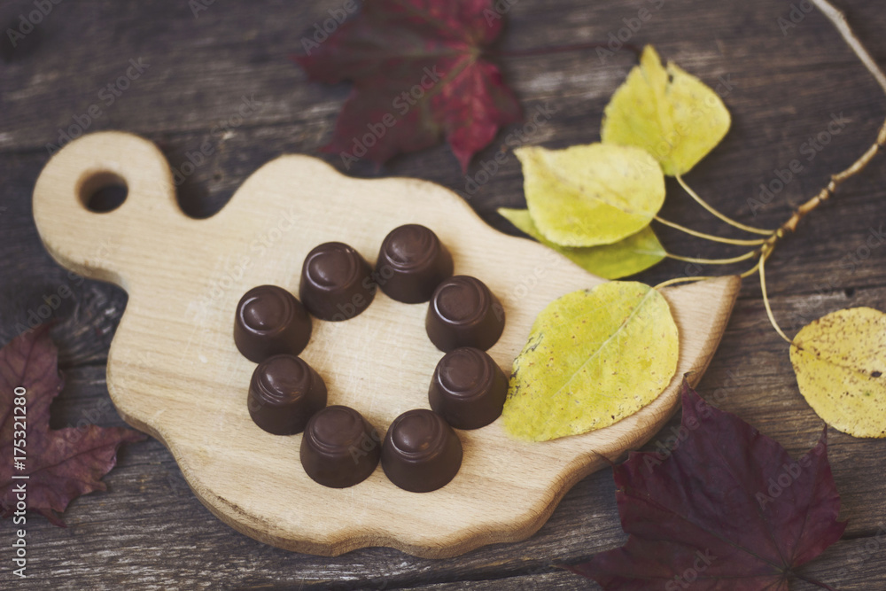chocolate candies on a wooden Board with autumn leaves chocolate candies on a wooden Board with autumn leaves