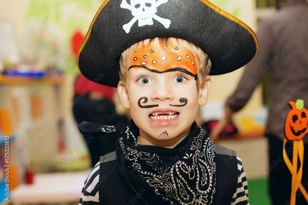 Halloween party. A little boy in a pirate costume and a makeup on his face  is having a good time at the Halloween party. Face painting kids. Stock  Photo