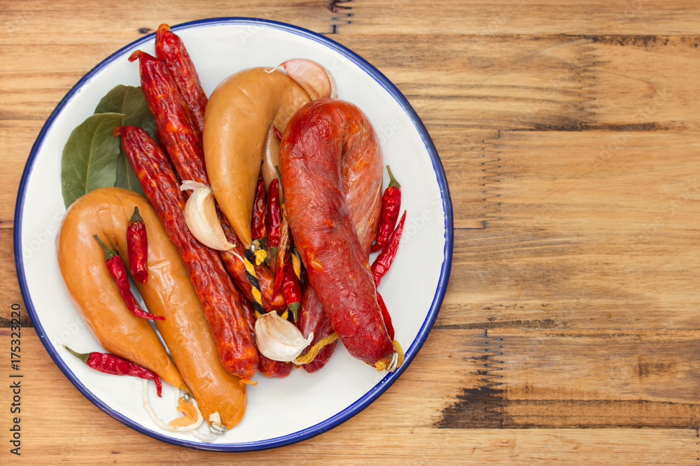 smoked sausages on white dish on wooden background smoked sausages on white dish on wooden background