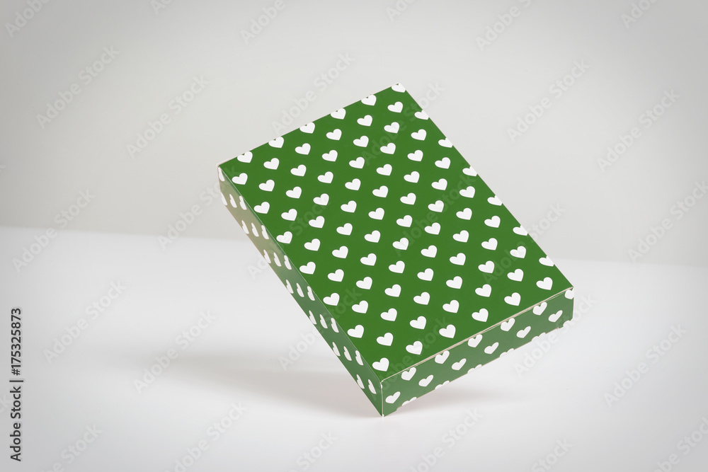 Green rectangular gift box with hearts in white floating in a grey background Green rectangular gift box with hearts in white floating in a grey background