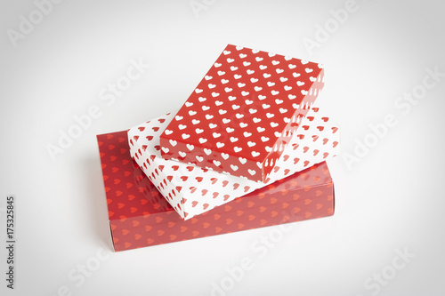 Three rectangular red gift boxes with hearts in red and white in a white background