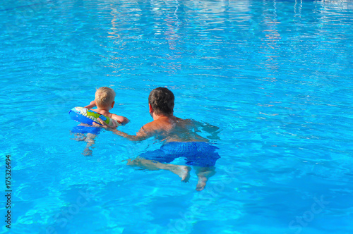 the little blonde boy of three years swim with swimming ring in an indoor pool with the father