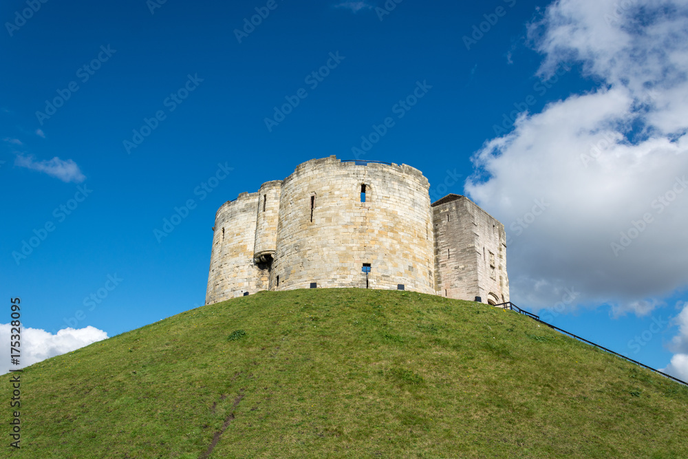 Clifford's Tower on grass covered hill with blue sky