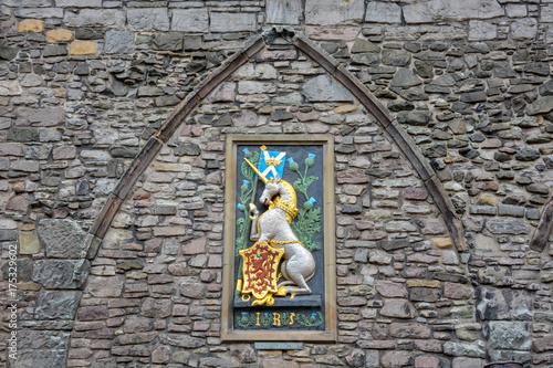 A unicorn with the Scottish flag and an emblem with a red lion on gold on a stone wall photo
