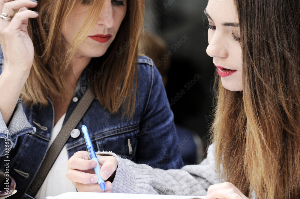 Attractive women are signing an agreement in an outdoor cafe. Lifestyle concept. Attractive women are signing an agreement in an outdoor cafe. Lifestyle concept.