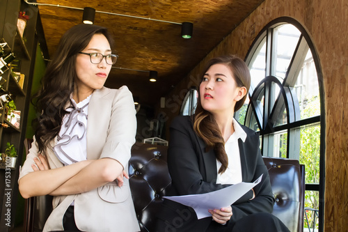 Fototapeta Two beautiful business woman, looking against with feel repulsion