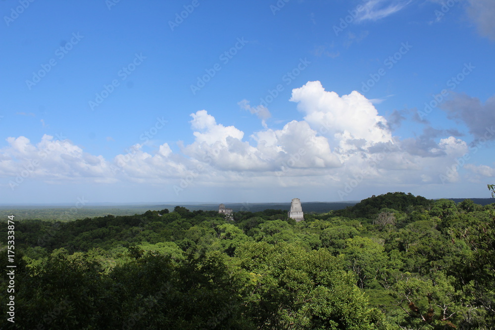 Due piramidi Maya che svettano dalla giungla in un cielo azzurro con nuvole bianche, Tikal, Guatemala