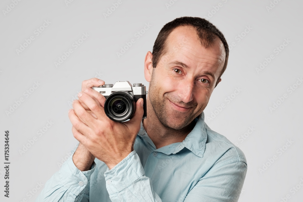 Mature caucasian man in blue t-shirt studing to use digital camera Mature caucasian man in blue t-shirt studing to use digital camera