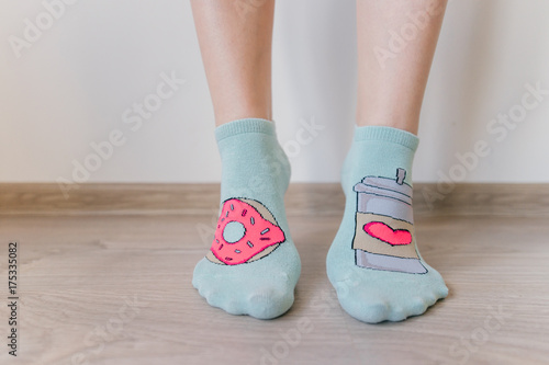 Female sexy naked legs standing on wooden floor in front of white wall. Women`s feet in short socks. Unrecognizable person. Femininity and tenderness concept. Soft and clear skin.