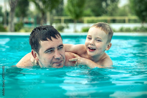 Father and son funny in water pool under sun light at summer da