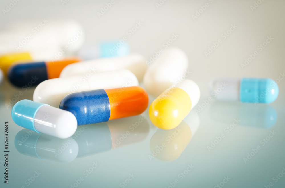 Pharmacy theme. Orange, Yellow, Blue, White Isolated Capsules on the White Surface. Closeup