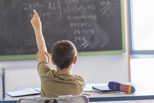 Student with hands up in classroom during a lesson