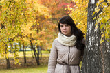 Girl near a tree against a background of autumn foliage