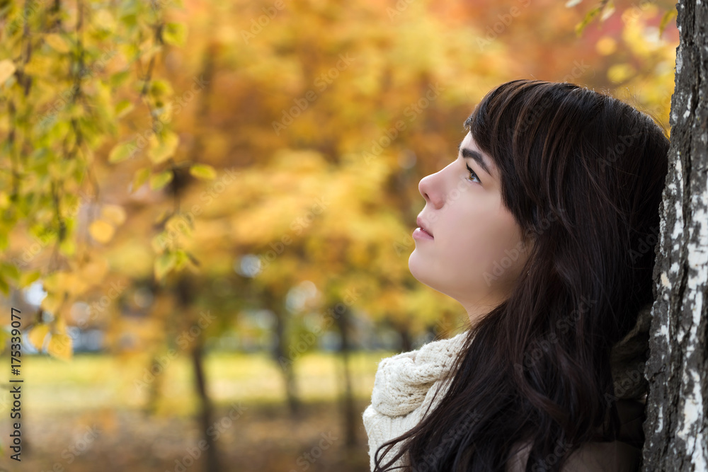 Girl near a tree against a background of autumn foliage Girl near a tree against a background of autumn foliage