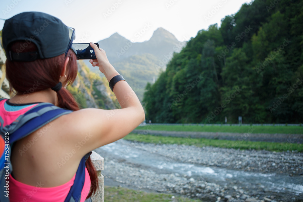 Image from back of tourist girl photographing mountain