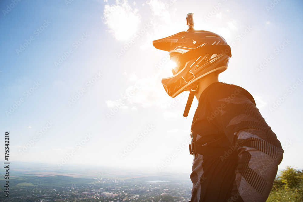 Portrait of a bicyclist in a full-face helmet and sunglasses against a background of a mountain