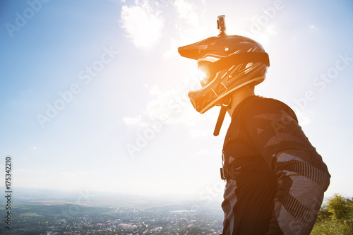 Portrait of a bicyclist in a full-face helmet and sunglasses against a background of a mountain © yanik88